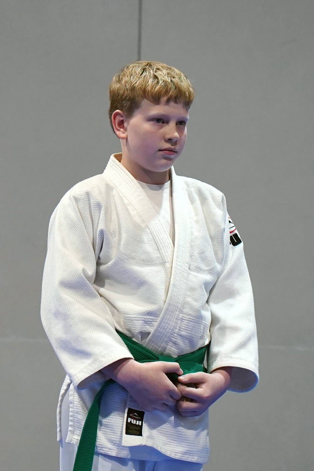 A green-belt student standing proudly on the mat at promotion night