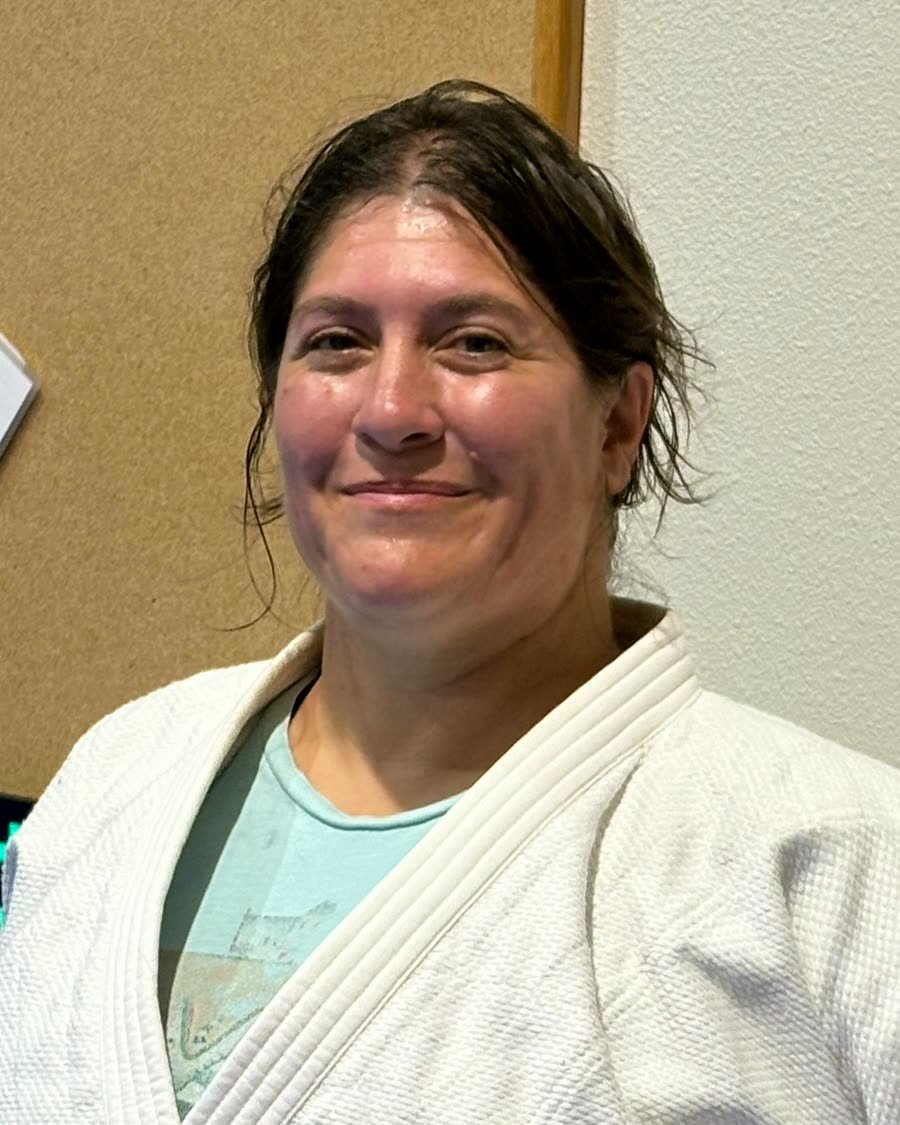 Coach Amy Carlisle smiling in a white judogi