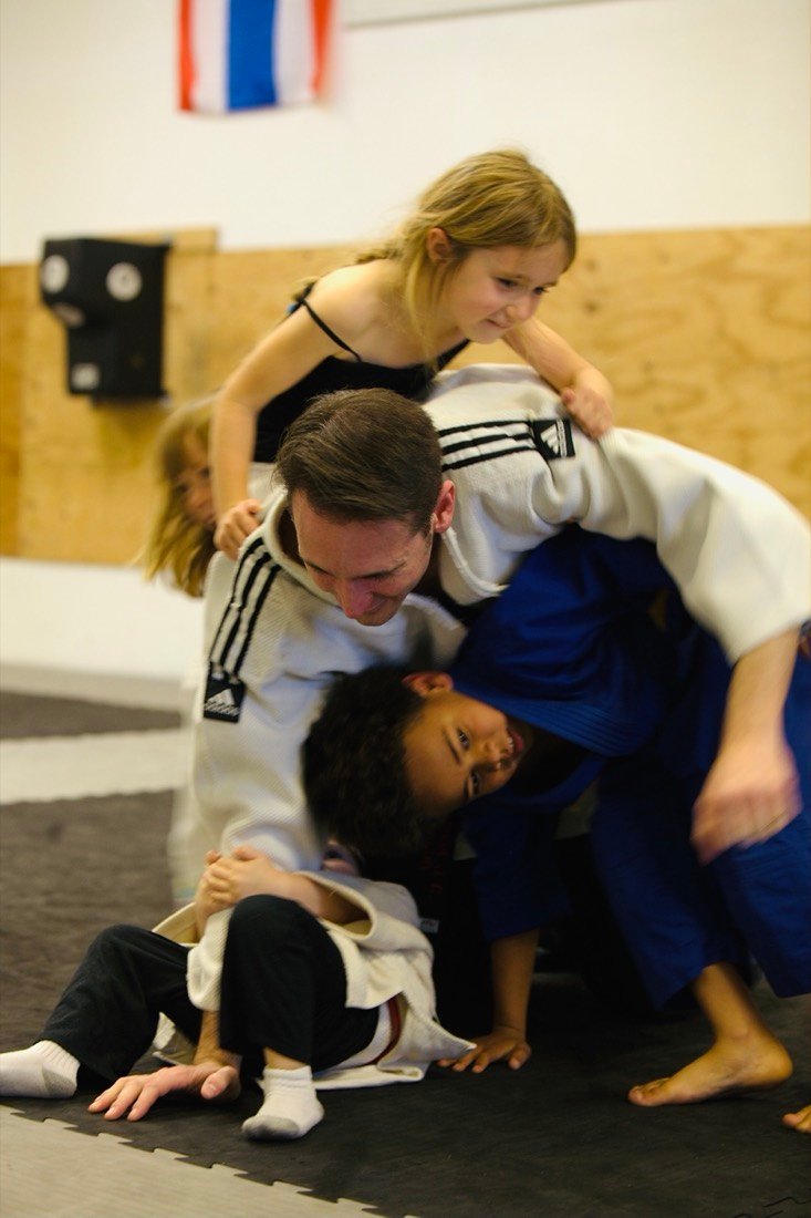 Coach Chris laughing as students pile on top of him during practice